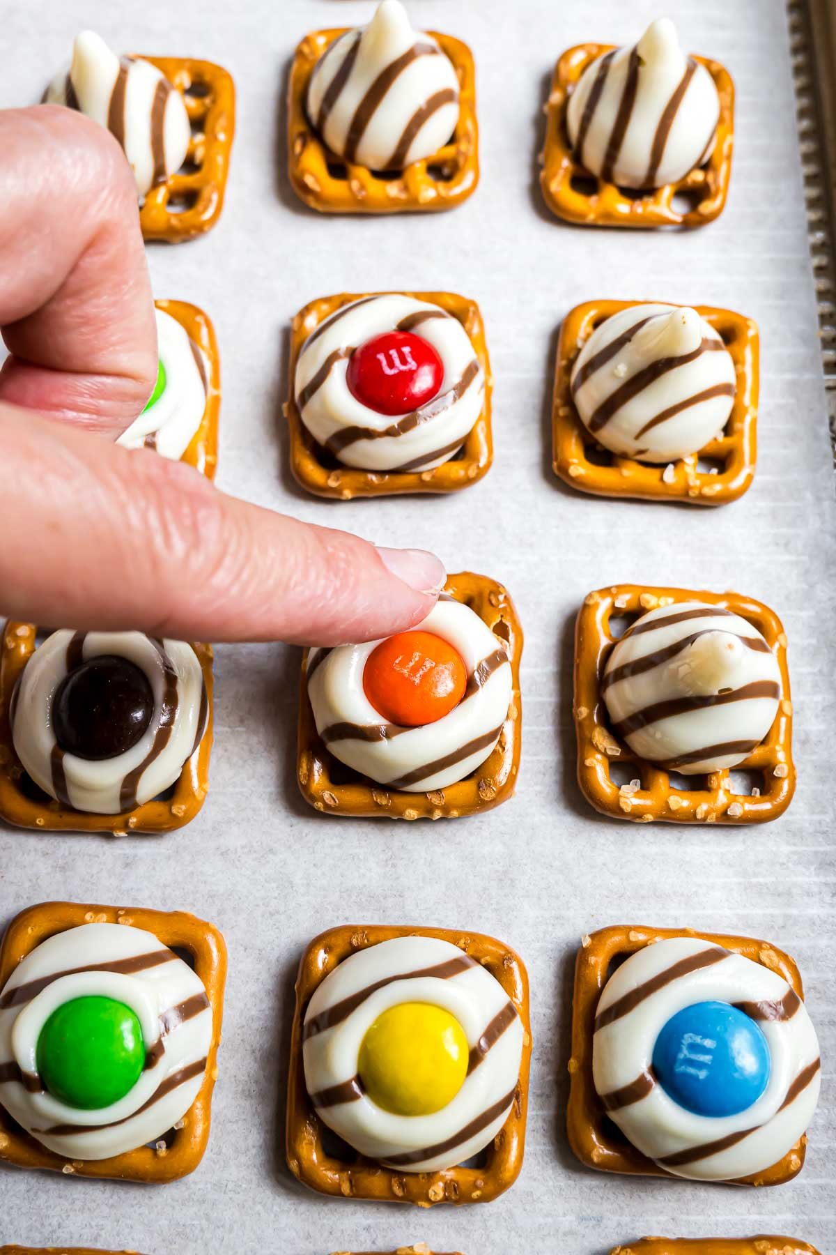 Pressing an M&M candy into the center of the softened Hershey's Hug.