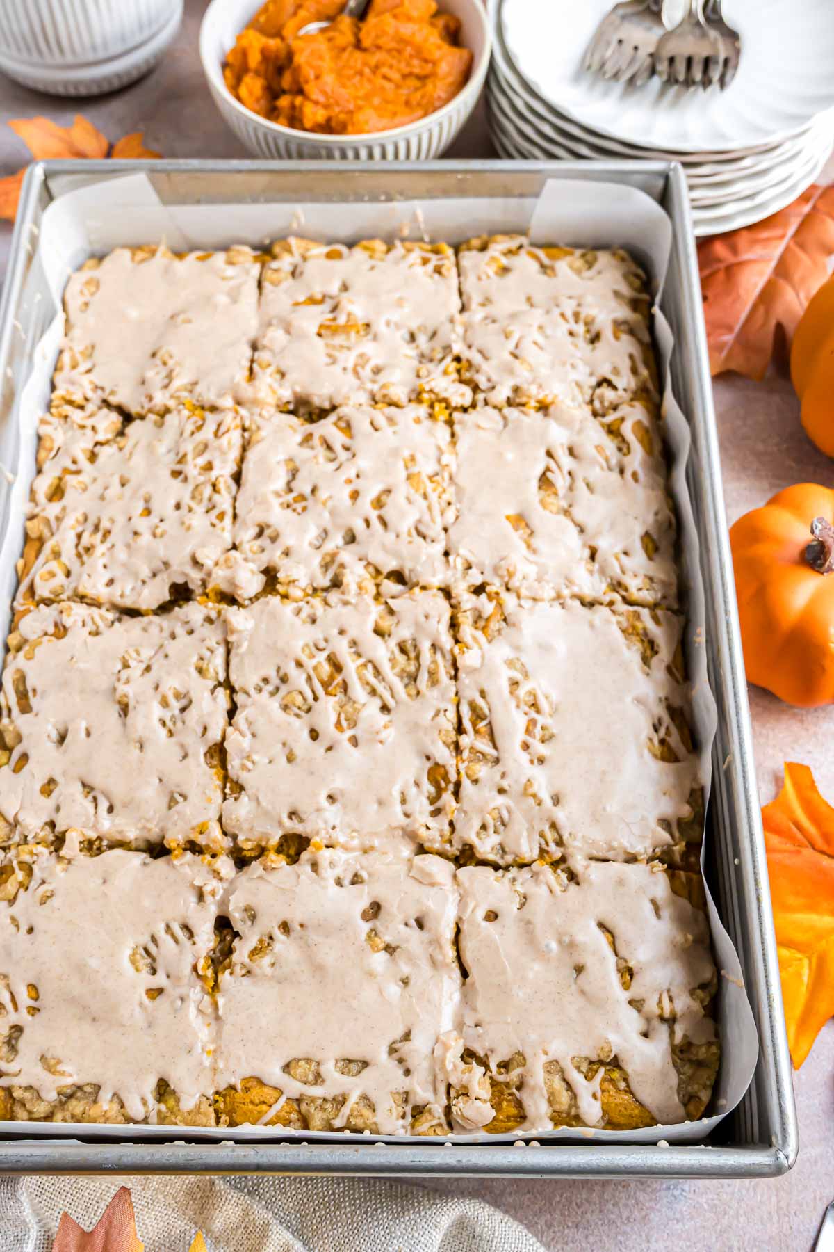 A metal rectangle baking pan with a pumpkin coffee cake in it. The cake is drizzled with cinnamon icing.