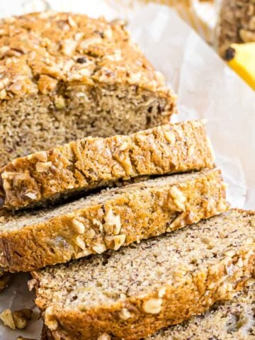 A loaf of banana nut bread that has been sliced and placed on a large serving platter.