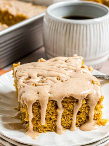 A piece of pumpkin coffee cake topped with cinnamon glaze on a small serving plate.