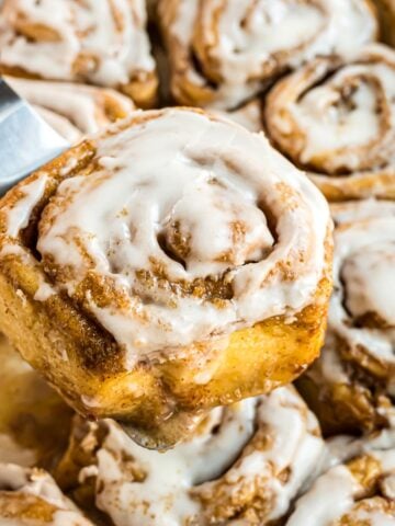 A Cinnamon Roll with Cream Cheese Icing on a spatula.
