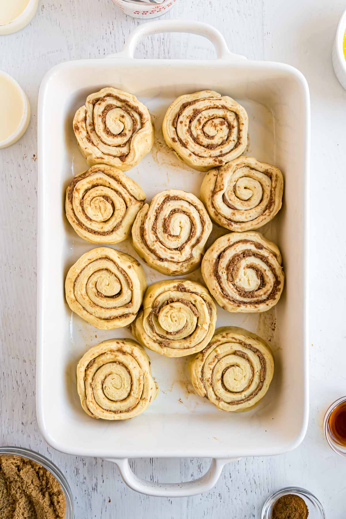 The cinnamon rolls in a baking dish before baking.
