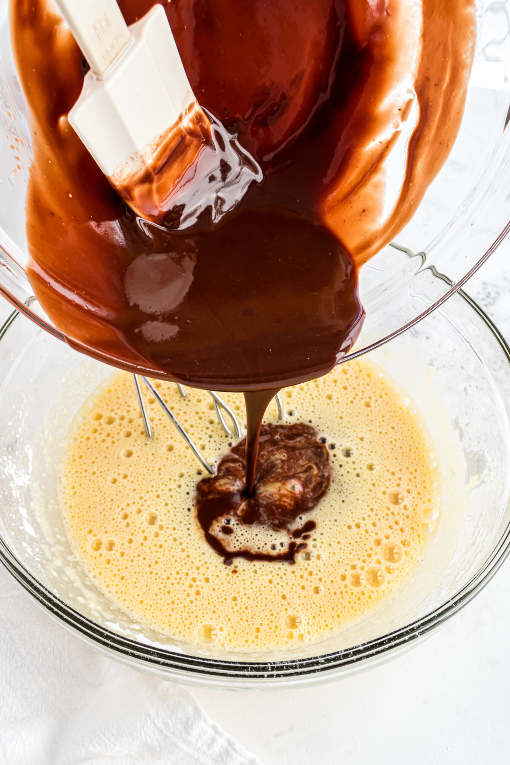 Adding the melted chocolate and butter mixture to the eggs.