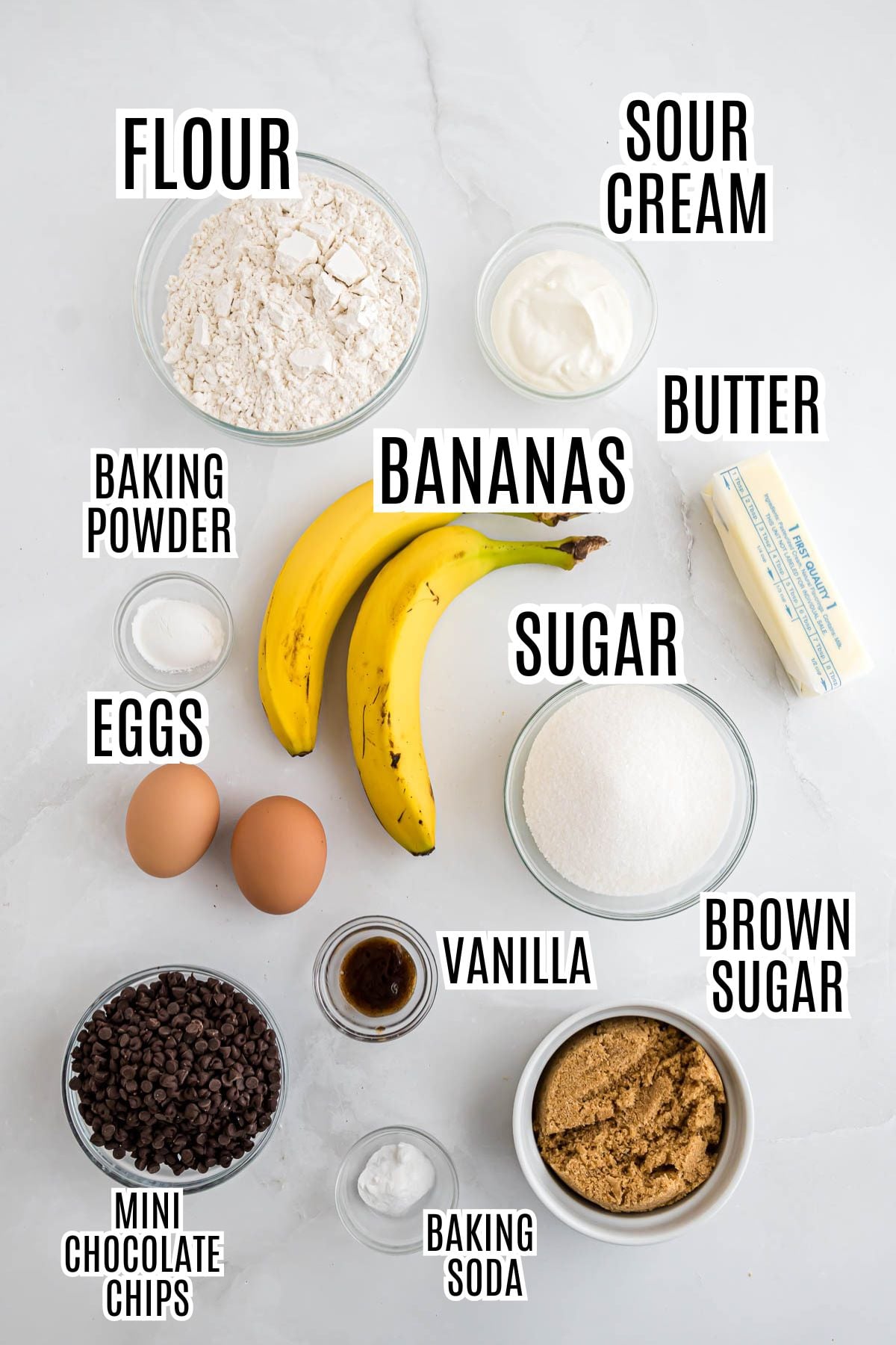 The ingredients needed to make the Banana Chocolate Chip Muffins include flour, sour cream, baking powder, bananas, butter, eggs, sugar, vanilla, brown sugar, mini chocolate chips, and baking soda.