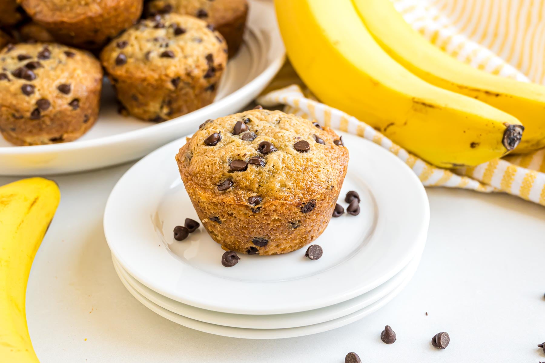 A freshly baked banana chocolate chip muffin on a small serving plate.