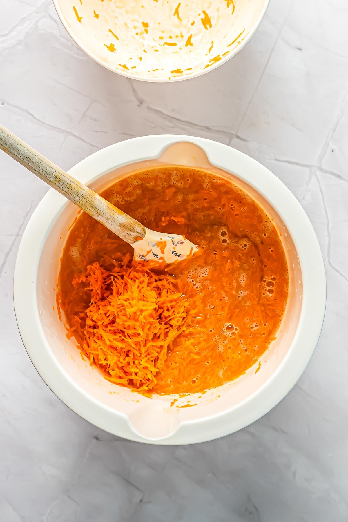 Adding the shredded carrots to the carrot cake batter.