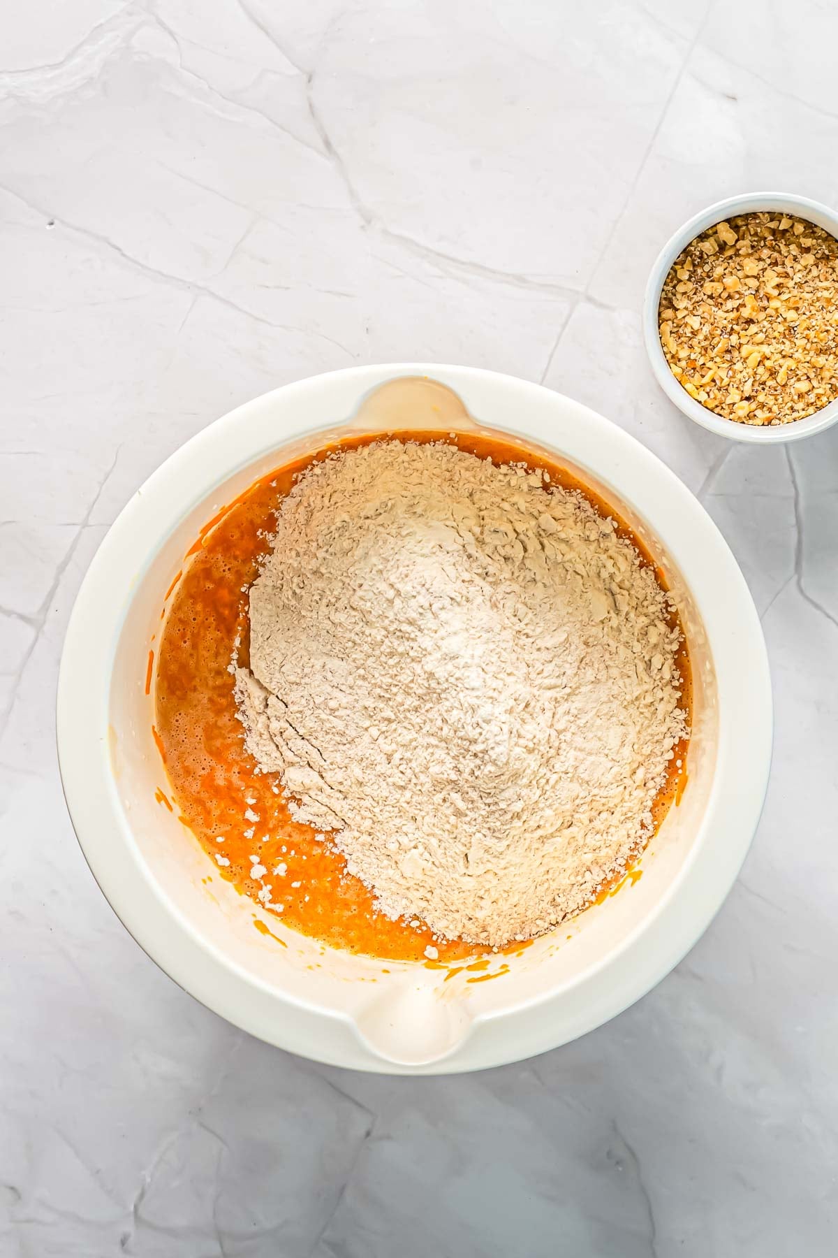 Adding the dry ingredients to the carrot cake batter.