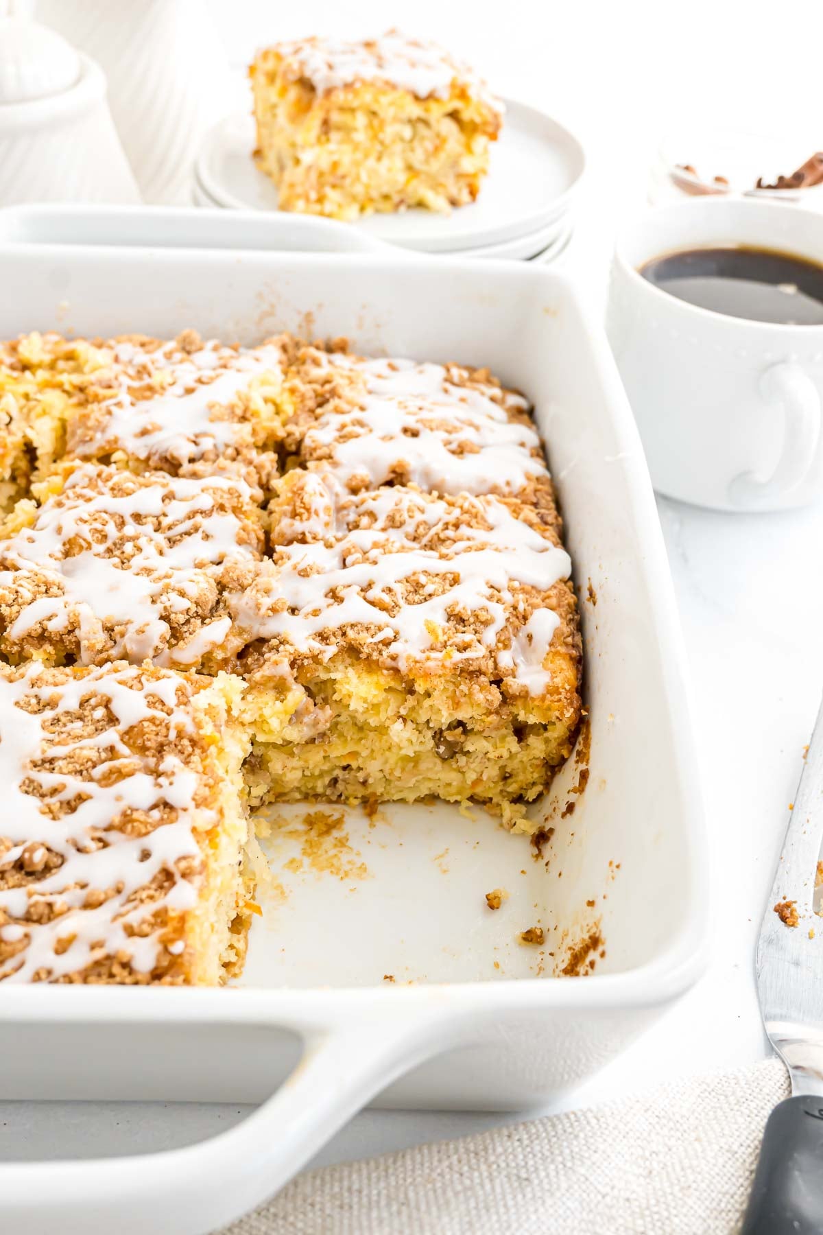 Morning Glory Cake in a 9x9 porcelain baking dish. There is a piece removed to reveal the texture and add-ins in the cake.