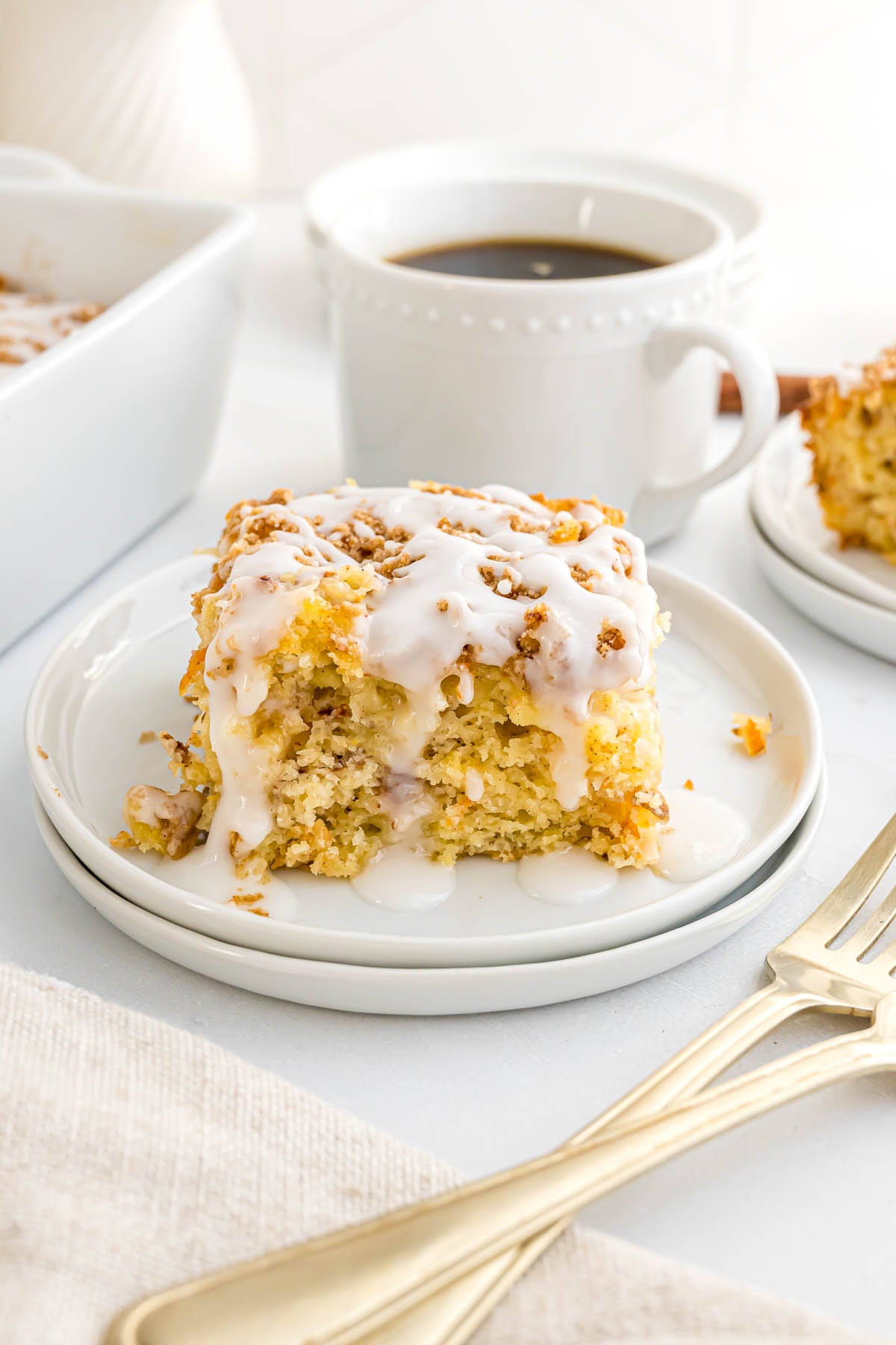 A piece of Morning Glory Cake on a small serving plate with coffee in the background.