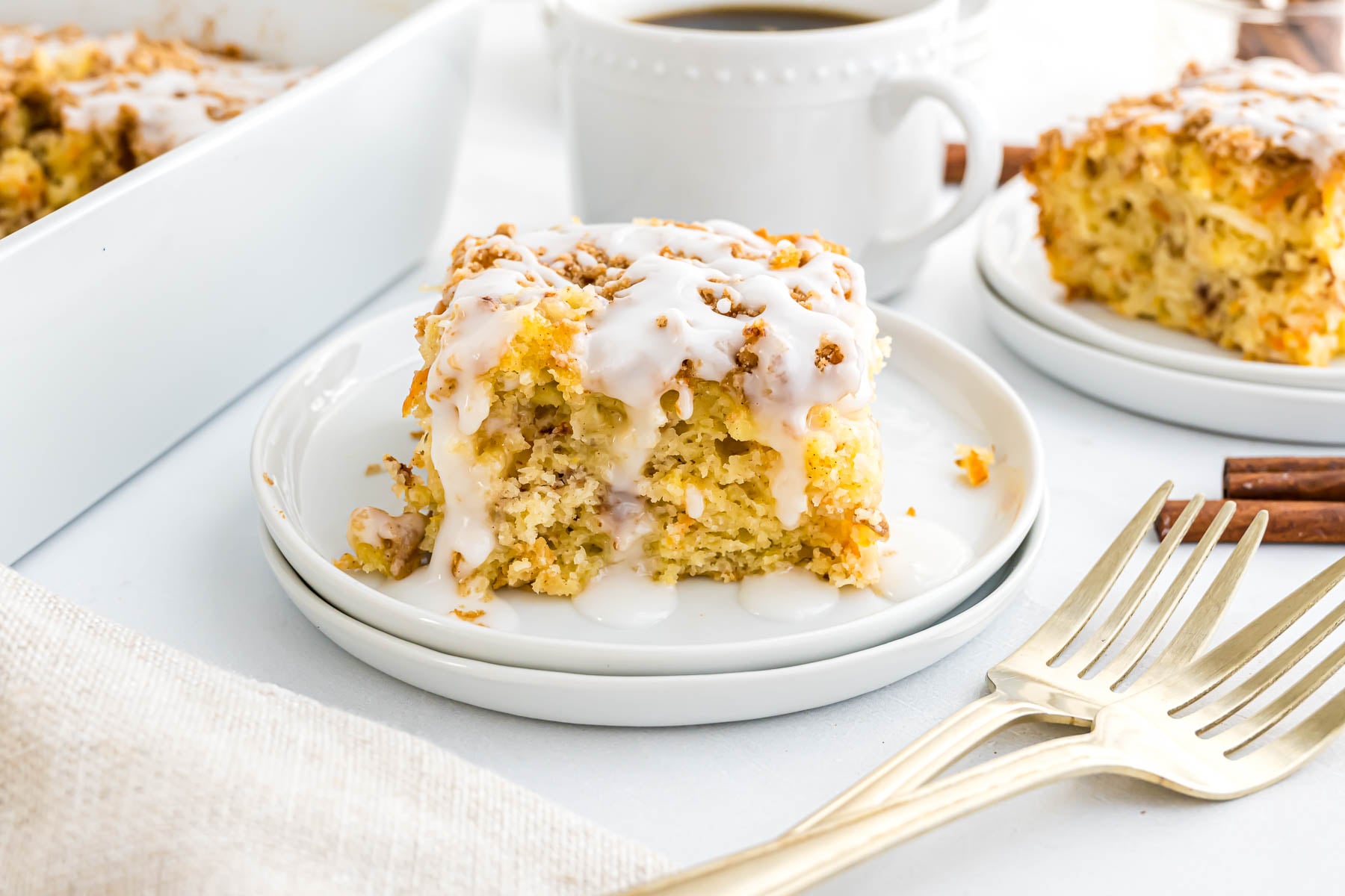 A piece of Morning Glory Cake on a small serving plate with coffee in the background.