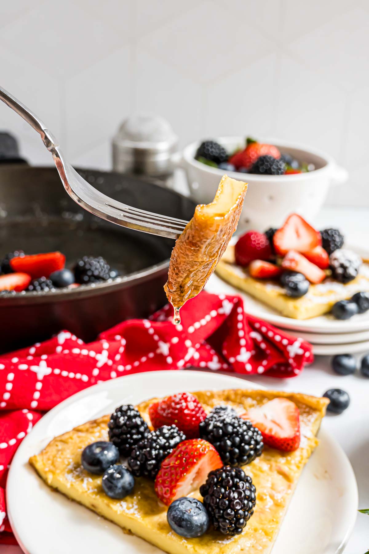 A bite of a Dutch Baby with syrup dripping off of it.