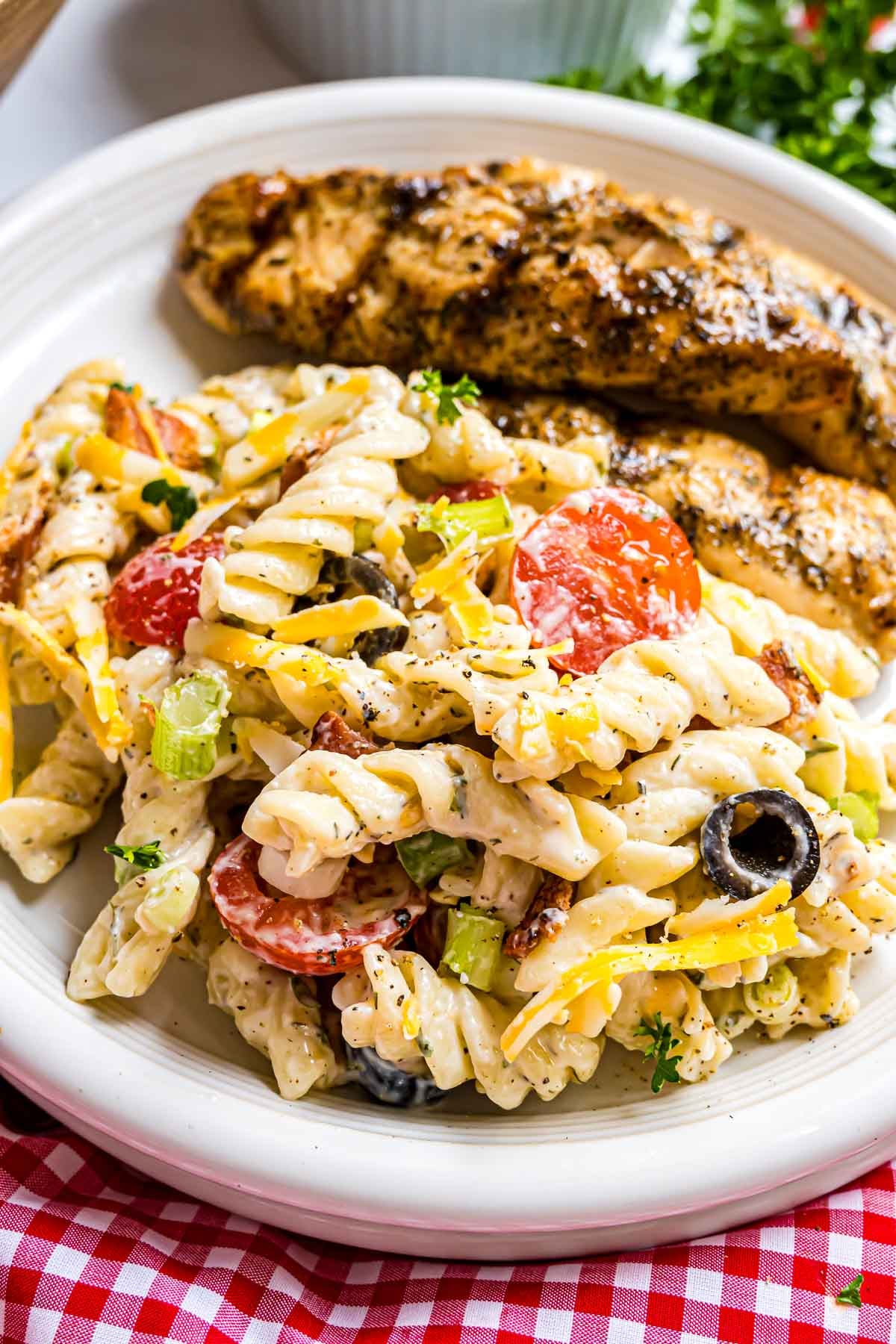 A plate featuring a generous serving of creamy Bacon Ranch Pasta Salad paired with a piece of grilled chicken.